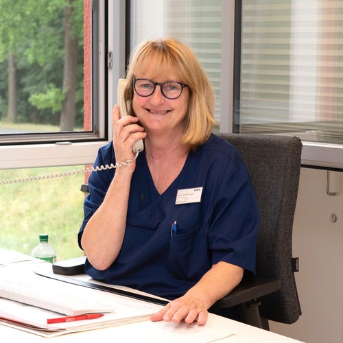 Eine lächelnde Frau mit blonden Haaren telefoniert